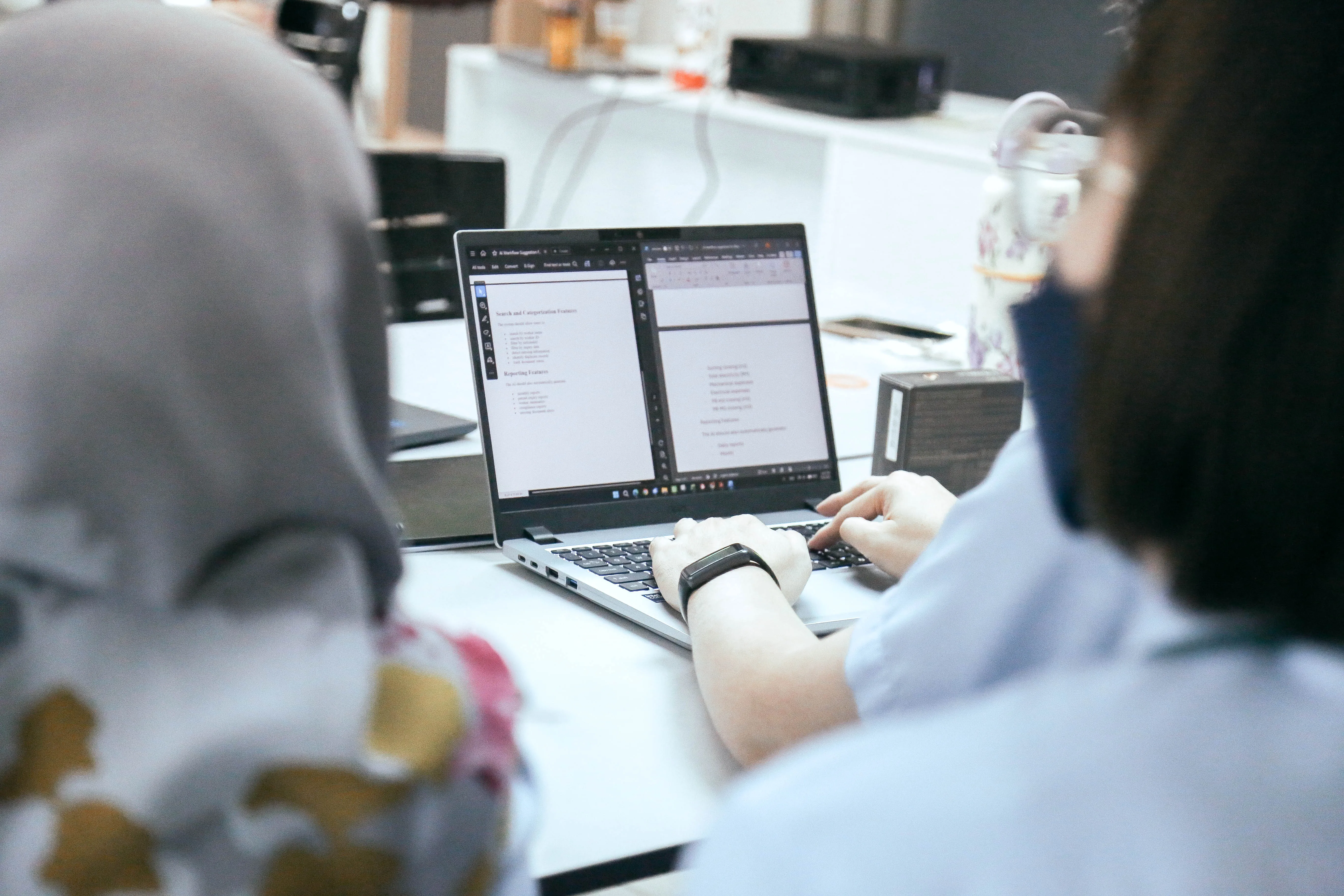 Participants reviewing an AI-assisted reporting workflow on a laptop during a working session